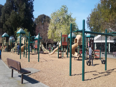 Community playground with multi-level play structures, slides, and climbing equipment on wood-chip surface