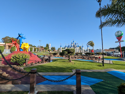 Mini golf course with colorful obstacles and castle in background under clear blue sky