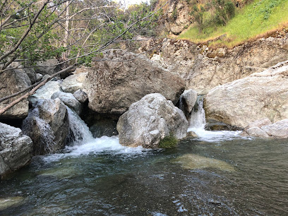 Water flowing over rocks in Alameda Creek with green hillside backdrop