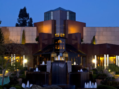 Modern architectural building with symmetrical design, illuminated at dusk with warm lighting and landscaping