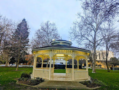 Yellow and green gazebo in public park with bare trees and grass
