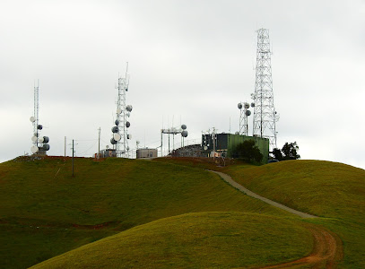 Communication tower facility on hilltop with green rolling terrain in Sunol area