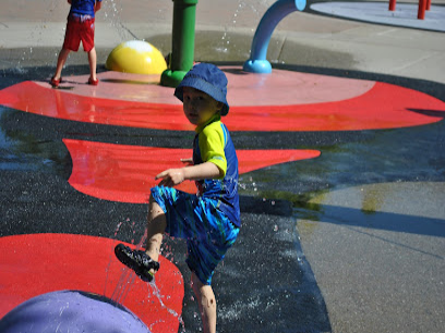Child playing on water pad with red and blue design at splash park