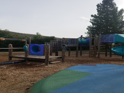 Community park playground with blue and green play structures on mulch ground