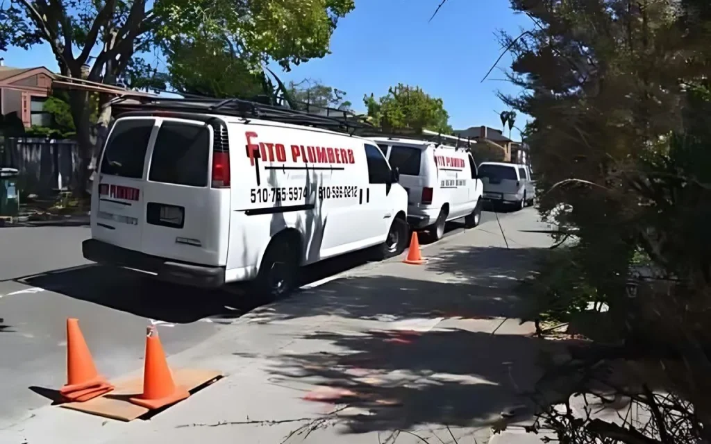 Fito Plumbers service vehicles parked on residential street with traffic cones