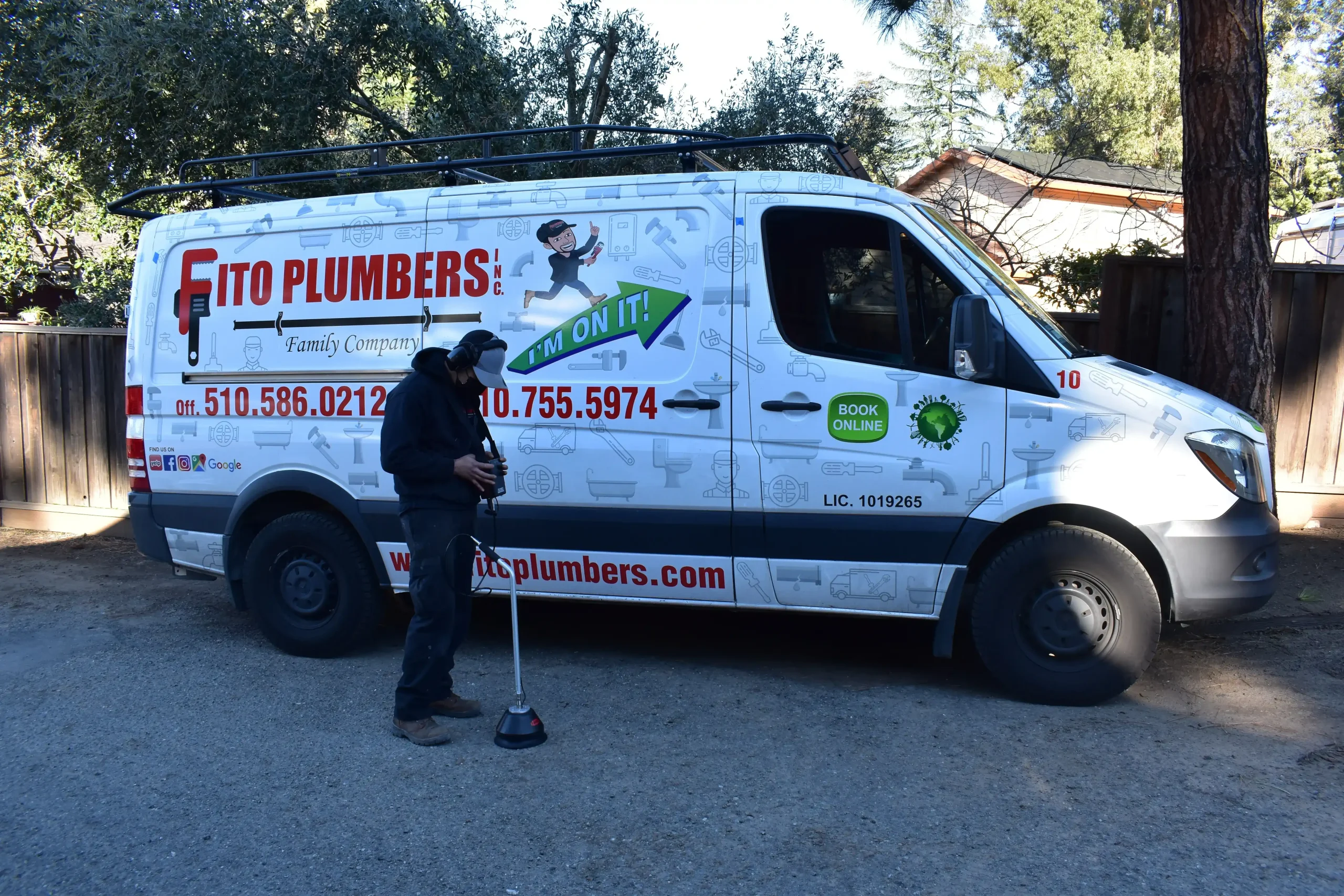 Fito Plumbers service van with technician holding plunger, displaying company logo, phone number, and website