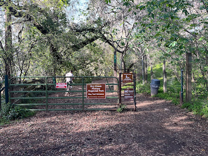 Wooden gate and signage marking entrance to wooded trail area with tall trees