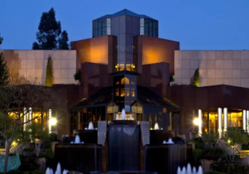 Modern museum building with symmetrical architecture illuminated at dusk, featuring dark facade and golden lighting
