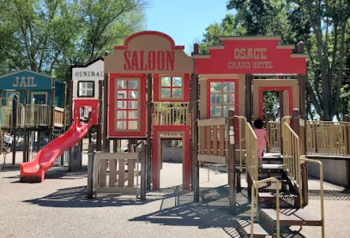 Saloon and Grand Hotel themed playground structure with red slide and wooden deck